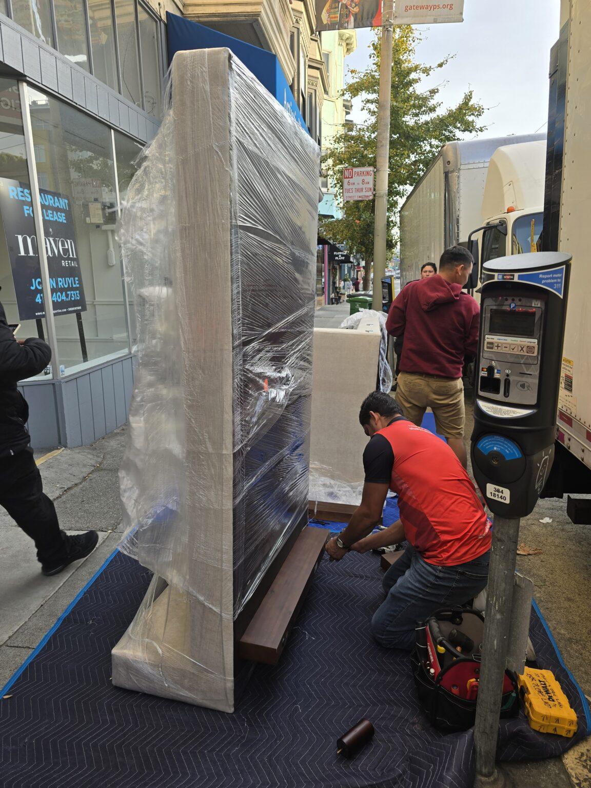 Moving crew protecting and transporting a large television in an urban area