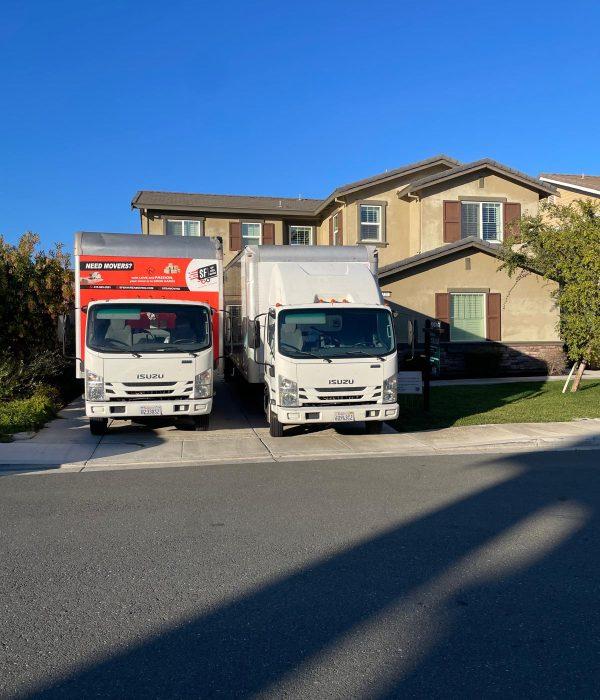 Two moving trucks parked in front of a suburban home during a residential move