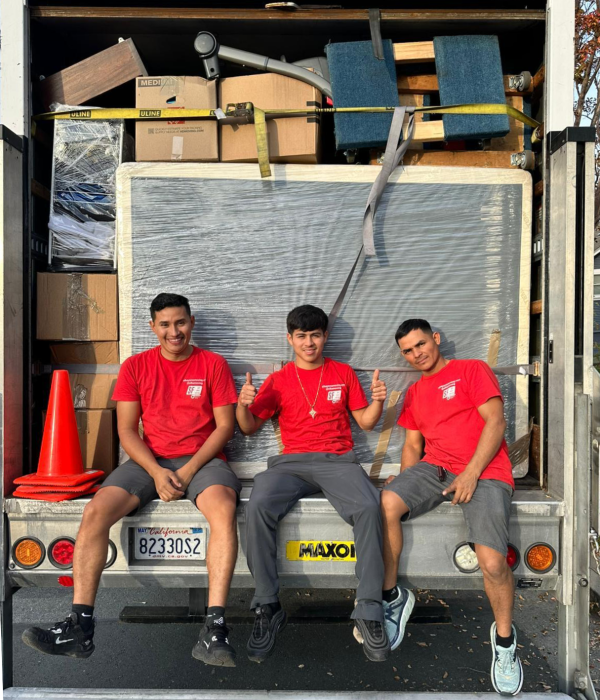 Professional moving crew sitting in a loaded truck with protected furniture and boxes