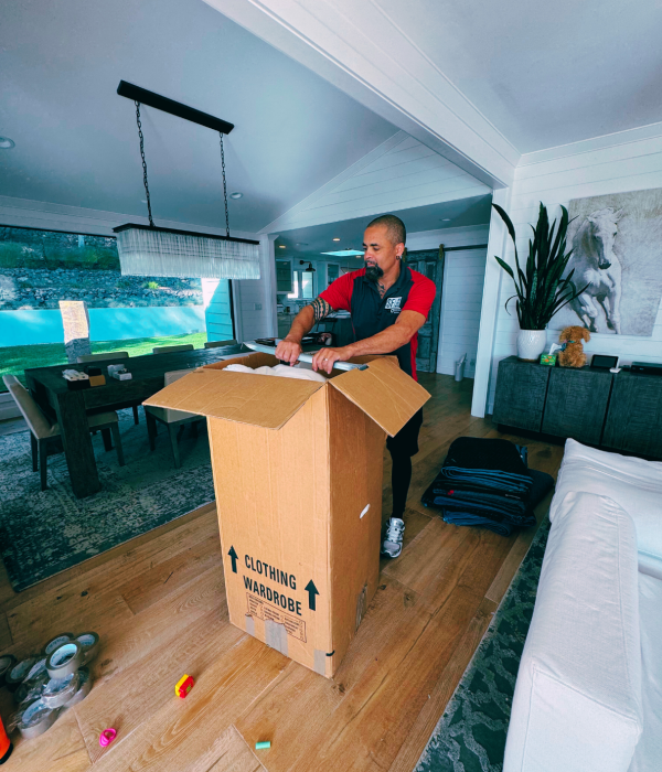 Moving crew member packing household items into a box